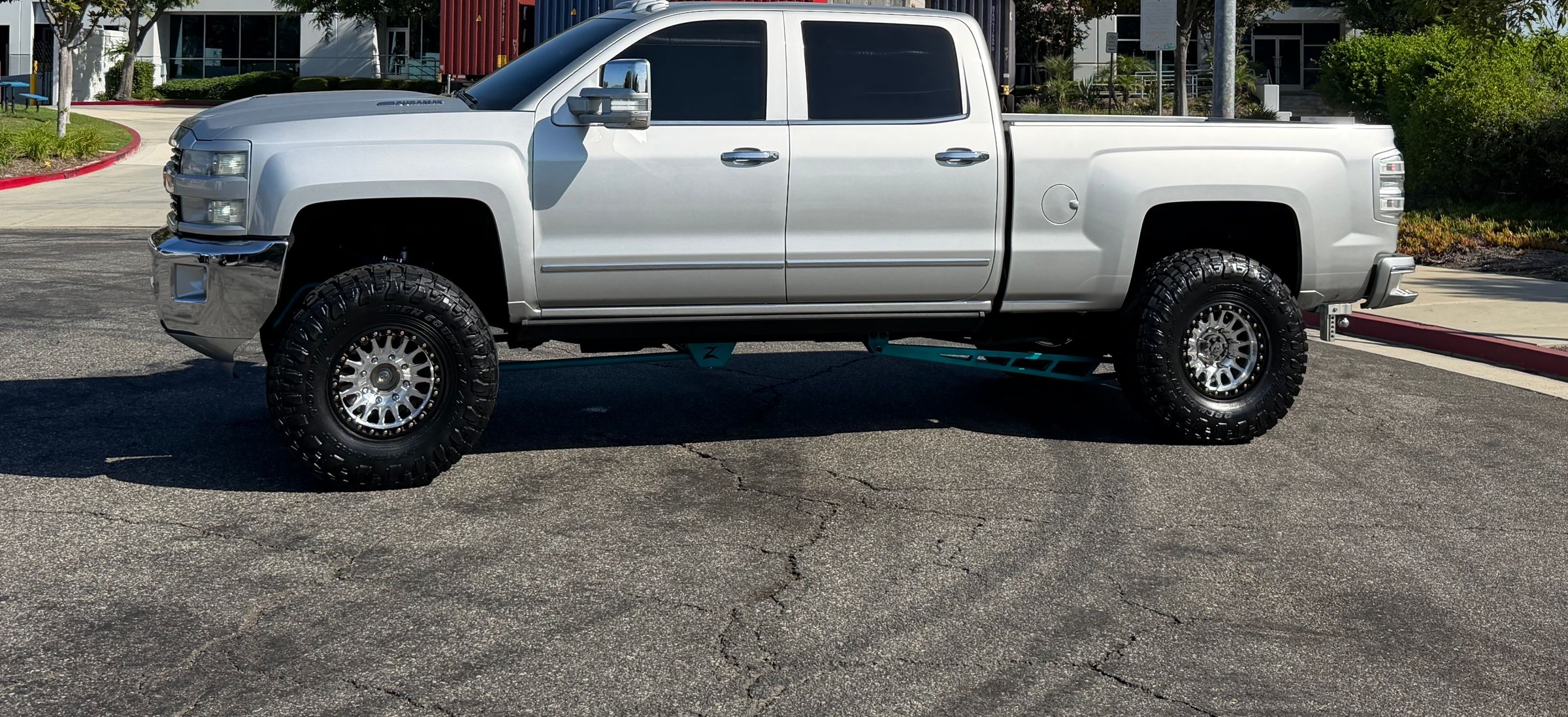 Lifted silver Chevrolet Silverado 2500HD, side profile at an industrial park