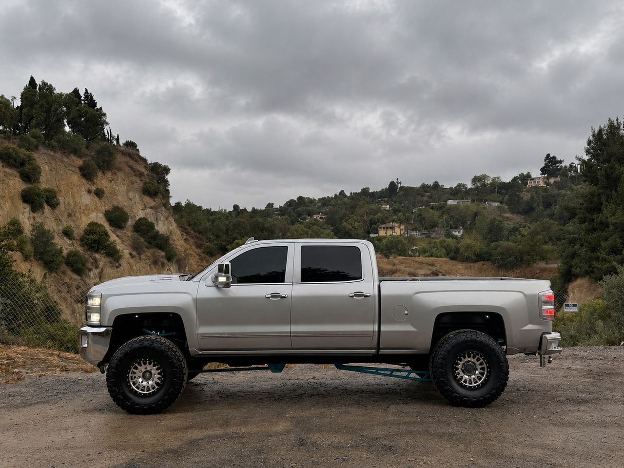 Lifted silver Chevrolet Silverado 2500HD Duramax, side profile under an overcast sky